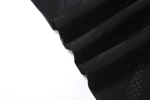 Détail du tissu en maille noire respirante avec texture plissée élégante sur la robe
