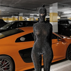 Detail of black glitter hooded bodysuit with face cover in an urban garage setting
