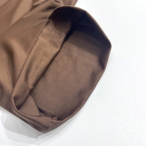 Detailed close-up of dark brown slim fit fabric with professional hemmed edge texture