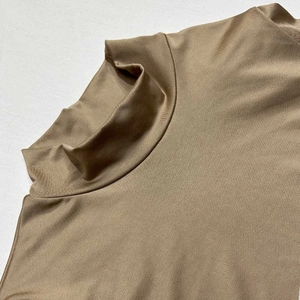 Détail d'un haut marron à col montant avec un tissu soyeux et une texture de col raffinée