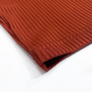 Detail view of rust-colored ribbed knit fabric texture and high-quality double stitching