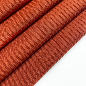 Detailed macro view of the rust orange ribbed knit fabric texture on a women's dress