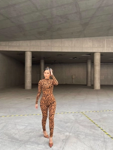 Close-up of leopard print bodysuit featuring a high neck and long sleeves on a model