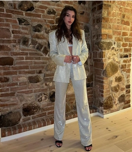 Dettaglio del blazer di paillettes e pantaloni a gamba larga in argento lucido