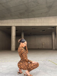 Detail view of tight-fitting leopard print jumpsuit with long sleeves and mock neck