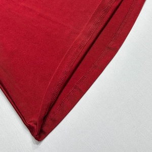 Close-up of the double-needle stitching and red knit fabric on the dress hem detail