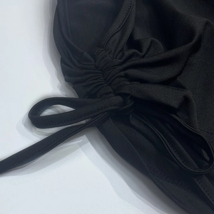Detail of adjustable drawstring and ruched design on black knitted mini skirt