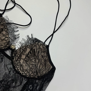 Détail de la dentelle florale noire avec boucle dorée et fines bretelles du haut
