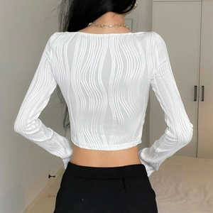Detail eines weißen Langarm-Cropped-Tops mit vertikal gewelltem Plissee-Stoffgewebe