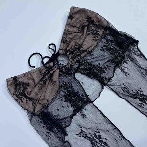Dettaglio del cardigan in pizzo floreale nero con fodera color carne e chiusura a lacci