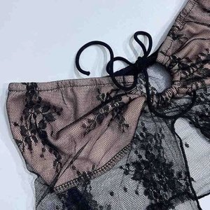 Dettaglio di un top in pizzo nero a fiori con ritaglio e delicato design a lacci