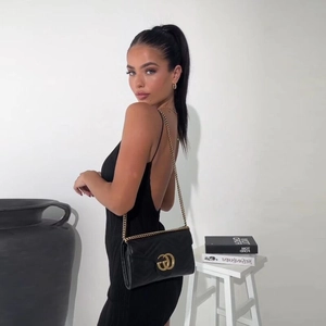 Détail d'un sac bandoulière en cuir noir matelassé avec une chaîne dorée chic