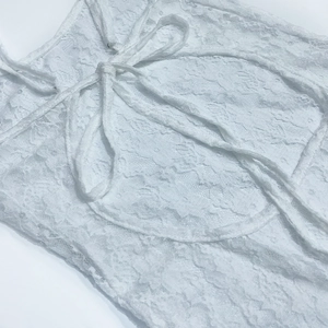 Gros plan sur la robe en dentelle blanche avec broderie florale et fines bretelles à nouer