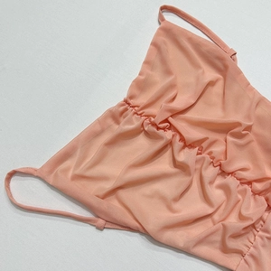 Détail du tissu en maille rose corail avec design froncé et fines bretelles