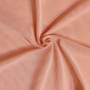 Gros plan sur la texture du tissu en maille rose chair de cette robe de soirée sexy