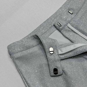 Dettaglio dei pantaloni argento glitterati con chiusura a gancio e barra nascosta