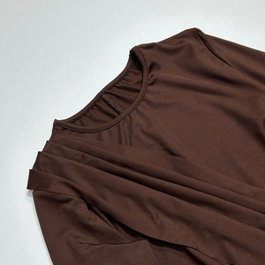 Dettaglio dell'abito in maglia marrone scuro con elegante scollo rotondo a pieghe incrociate
