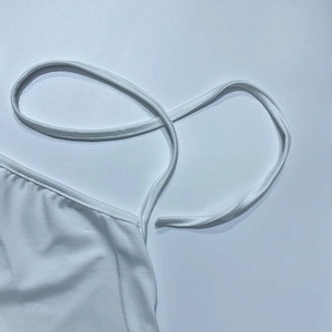 Close-up detail of white halter neck dress featuring thin straps and fine stitching work