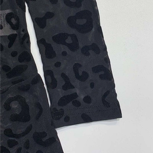Close-up of black mesh jumpsuit featuring velvet flocked leopard print with sheer texture