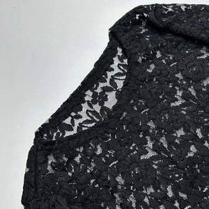 Dettaglio dei delicati motivi floreali in pizzo nero e scollo rotondo sull'abito