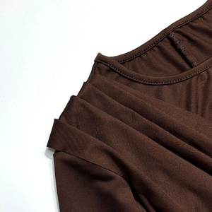 Dettaglio delle pieghe sulle spalle di un abito aderente in maglia marrone scuro