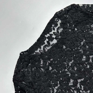 Dettaglio dell'abito in pizzo nero con motivo floreale all'uncinetto sulle spalle
