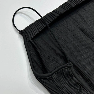 Détail de la texture plissée noire et de la fine bretelle sur une robe d'été minimaliste
