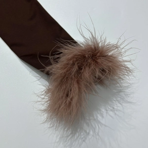 Dettaglio ravvicinato di maniche in maglia color cioccolato con bordi in morbide piume rosa