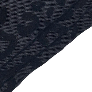 Macro shot of black leopard print flocking on sheer mesh fabric of the jumpsuit