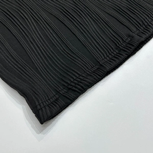 Détail du tissu plissé noir avec des coutures fines et une texture à rayures verticales