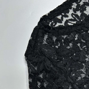 Dettaglio del ricamo floreale in pizzo e della trama trasparente dell'abito nero