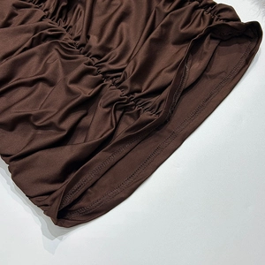 Dettaglio ravvicinato dell'increspatura e delle cuciture su un vestito marrone
