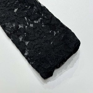 Dettaglio ravvicinato della trama in pizzo nero floreale sulla manica del vestito