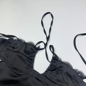 Détail d'un haut en satin noir avec dentelle de cils délicate et texture soyeuse