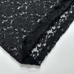 Dettaglio del tessuto in pizzo nero con motivi floreali a rose e trama a rete fine