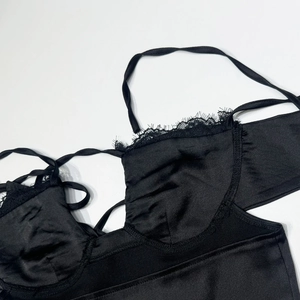 Détail d'un caraco en satin noir avec bordure en dentelle cil et bonnets style lingerie