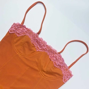 Détail d'un caraco orange avec bordure en dentelle florale rose et fines bretelles