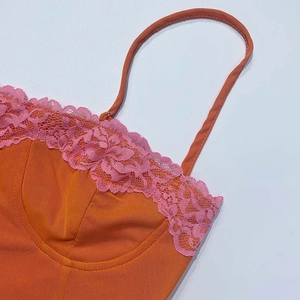 Détail d'un caraco orange en mesh avec bordure en dentelle florale rose délicate