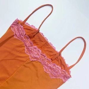Détail d'un caraco orange avec bordure en dentelle rose et fines bretelles