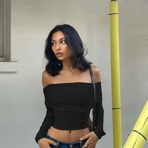 Nauwsluitende zwarte crop top met blote schouders, lange mouwen en geplooide voorkant