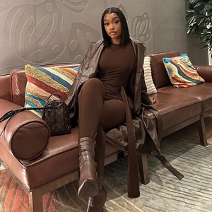 Close-up of brown leather textured long coat and matching slim-fit bodysuit outfit