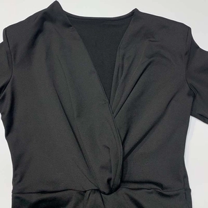 Detailaufnahme des tiefen V-Ausschnitts mit Knotendesign und Faltenstruktur am schwarzen Kleid