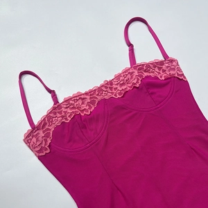 Détails de la bordure en dentelle rose et des coutures corset sur le haut satiné