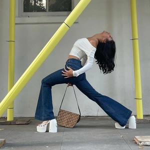 Detail van een sexy witte off-shoulder crop top gecombineerd met flared denim jeans