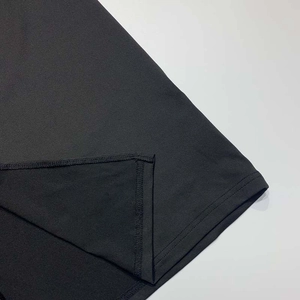Detaillierte Nahaufnahme der feinen Saumnaht und des elastischen Strickstoffs am schwarzen Kleid