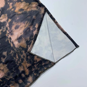 Vue détaillée du tissu tie-dye avec couture overlock noire et texture de l'ourlet