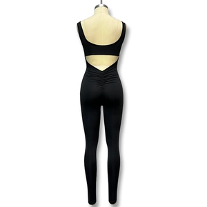 Detail of backless black athletic jumpsuit featuring ruching detail and elastic fabric