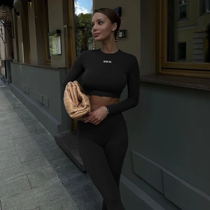 Close-up of black ribbed crop top featuring small white text print and high-waist joggers