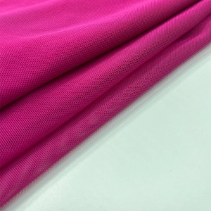 Vue détaillée du tissu en maille rose rouge avec une texture fine en nid d'abeille