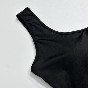 Close-up van de brede schouderbanden en U-hals van een zwarte nauwsluitende yoga bodysuit